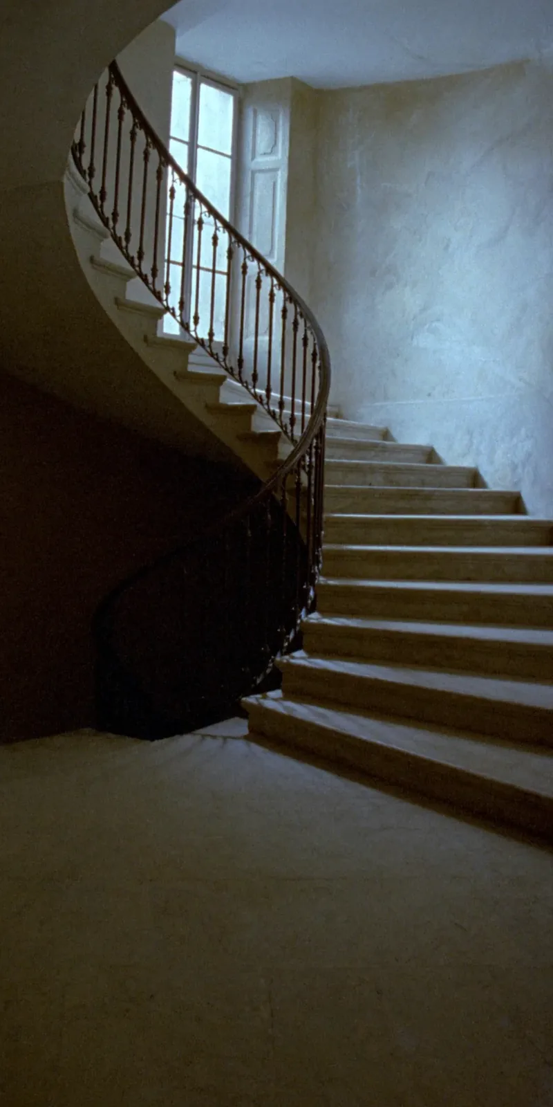 The stone staircase, lit by a tall window.